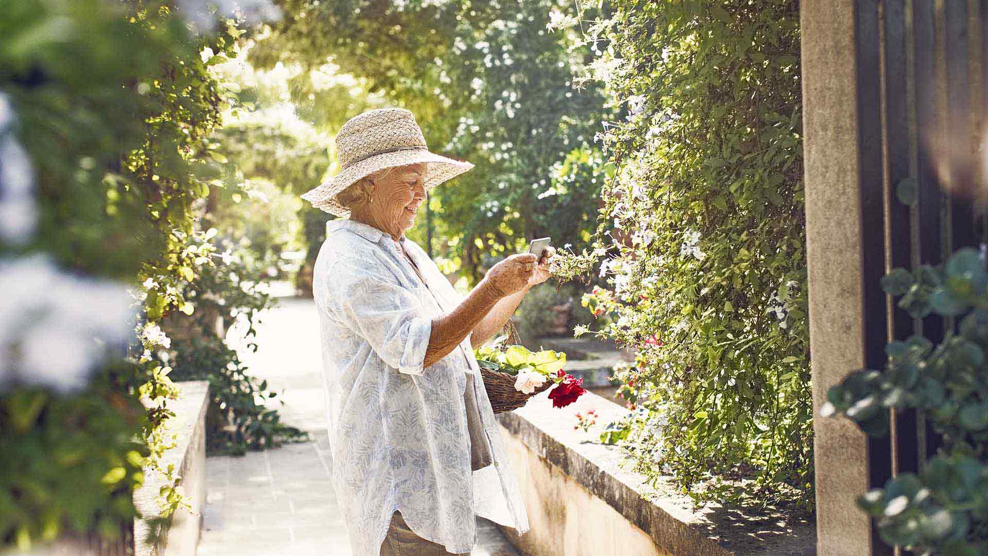 Donna anziana che raccoglie dei fiori in giardino